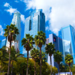Los Angeles downtown skyscrapers with palm trees and Pershing Square in the foreground with clouds and a blue sky in the background