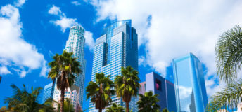 Los Angeles downtown skyscrapers with palm trees and Pershing Square in the foreground with clouds and a blue sky in the background